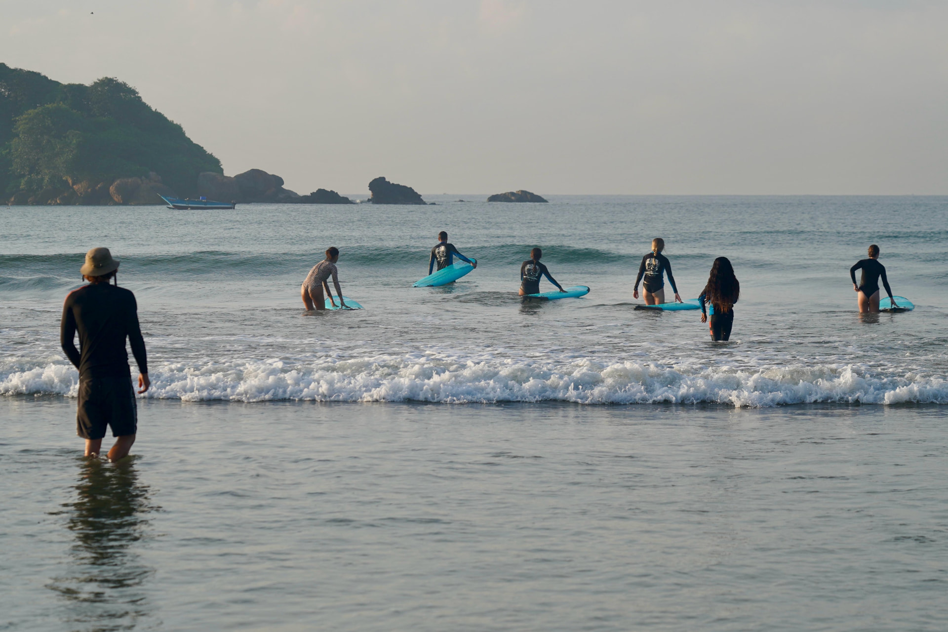 Surf students walking out into the shore break with boards