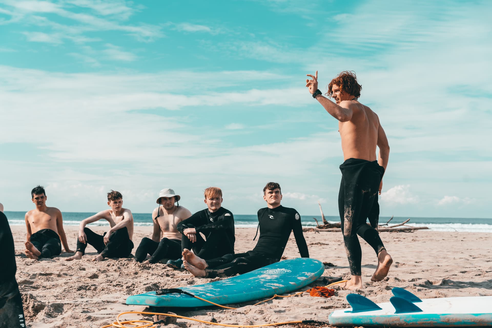 Surf coach briefing a group of students on the sand