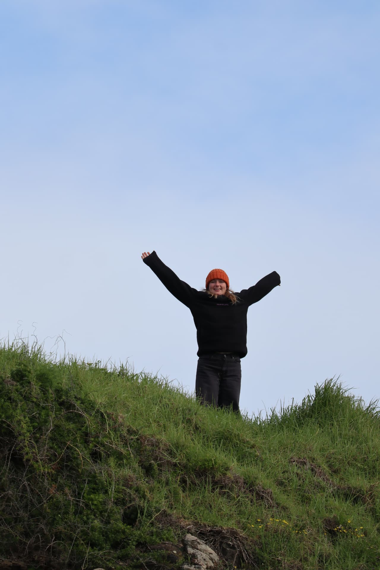 Surfer celebrating on a grassy coast with open sky
