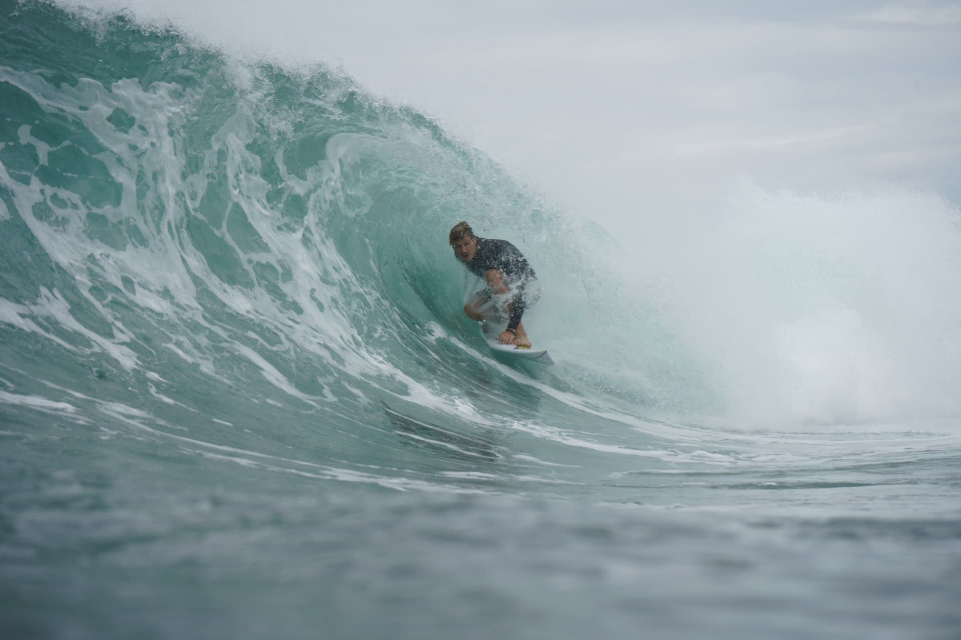 Surfer riding deep inside a clean barrelling wave